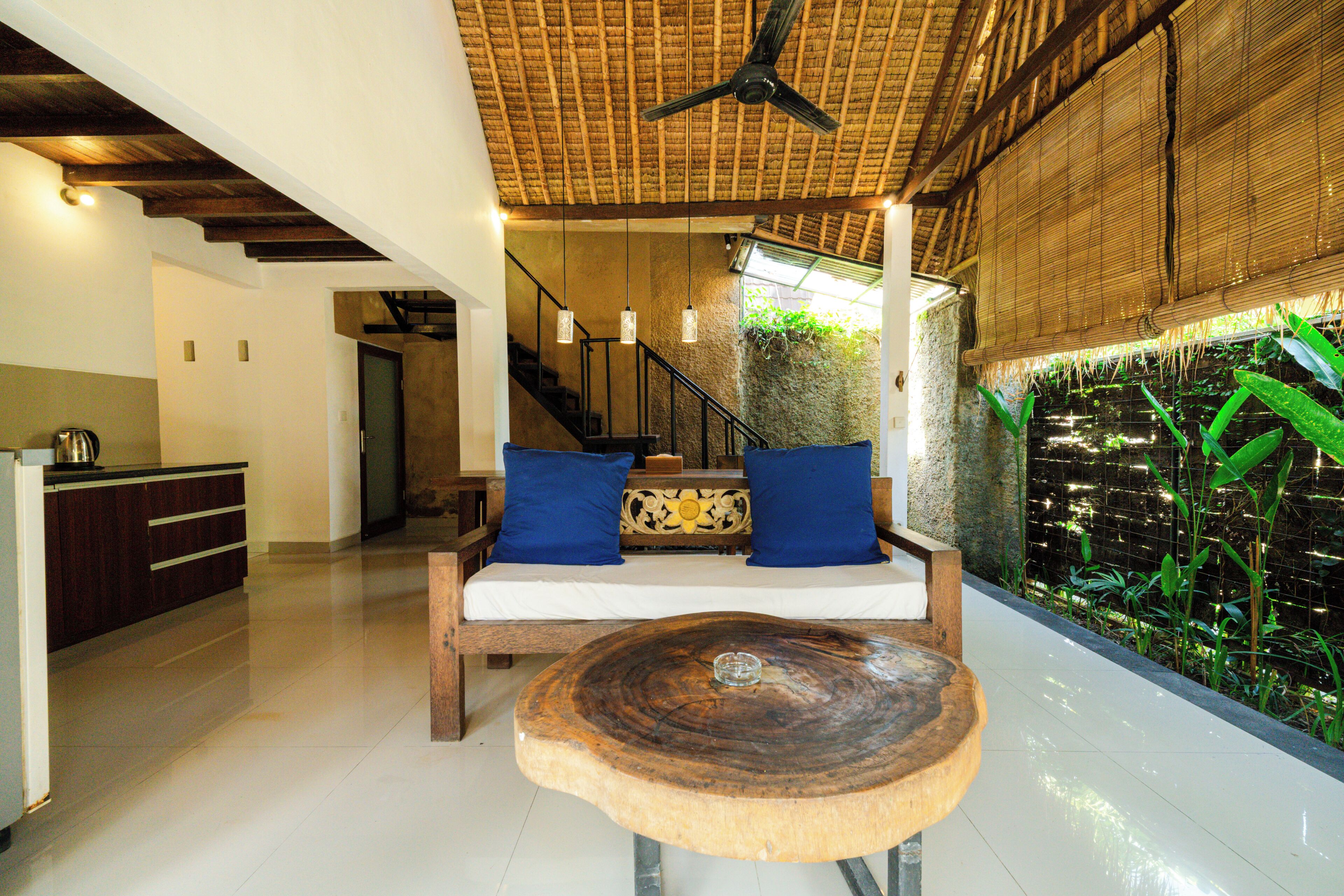 A room with a wooden bench, a staircase, and a wall with green plants.