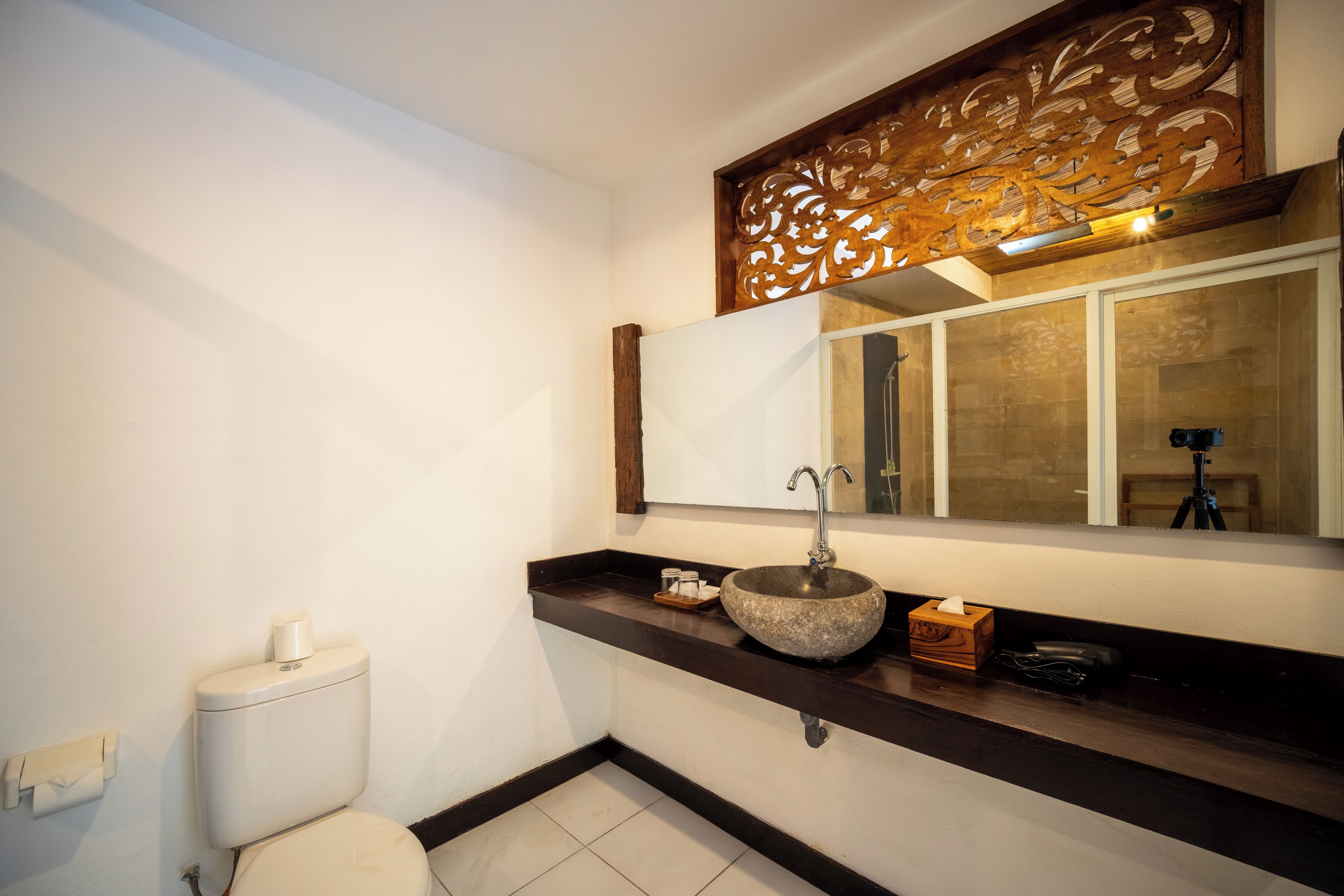Un baño moderno con un lavabo de piedra, un inodoro y un tocador con espejo.