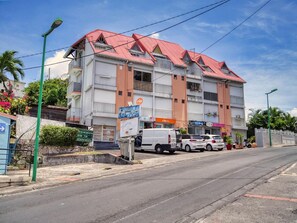 A multi-story building with a red roof, a sign for a restaurant, and a parked van. - Ocean view, close to all amenities (Saint-François)