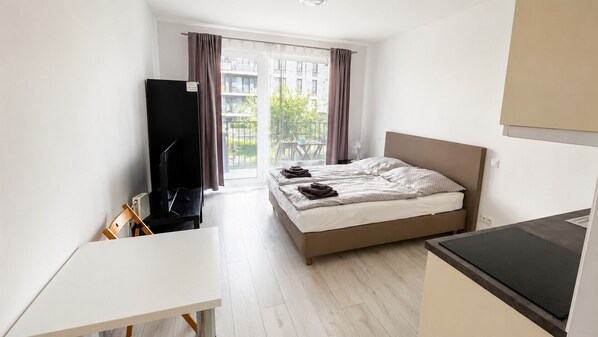 A hotel room with a bed, a desk, a television, and a view of the outside.