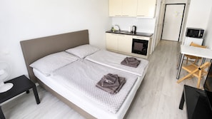 Ein Hotelzimmer mit einem Bett, einem Schreibtisch, einem Stuhl, einer Mikrowelle und einer Küchenzeile.