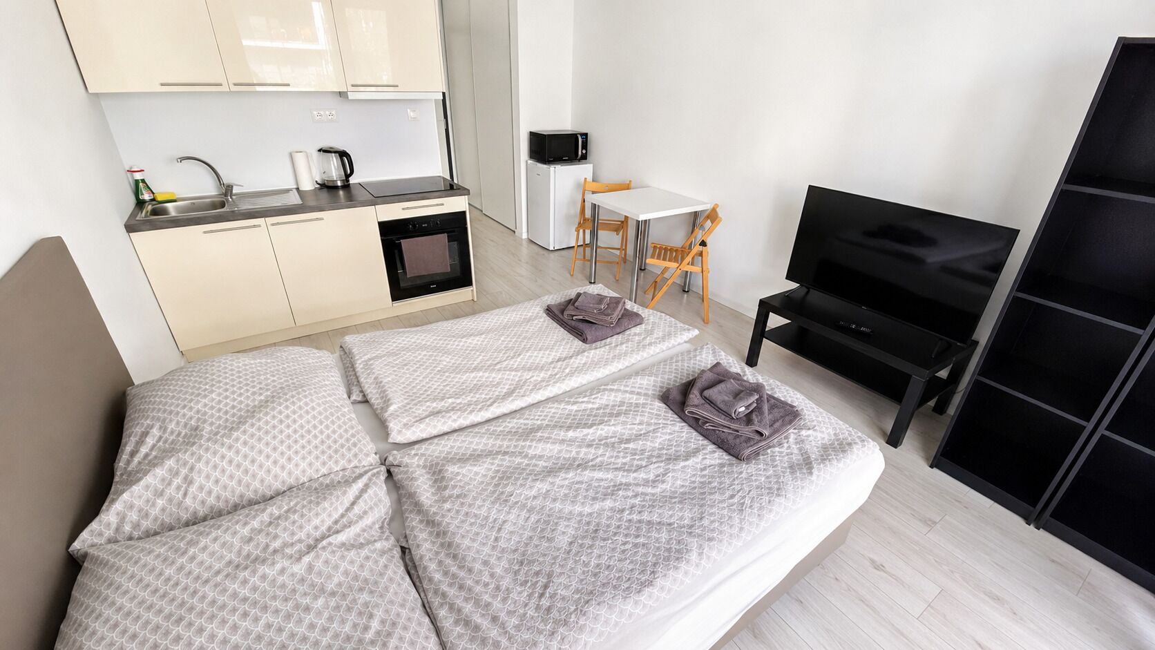 Bright studio with kitchenette, twin beds, TV, and dining nook