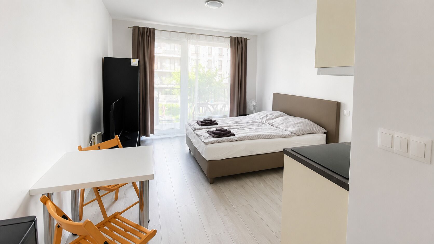 A hotel room with a bed, a desk, a chair, and a television.