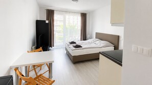 A hotel room with a bed, a desk, a chair, and a television.