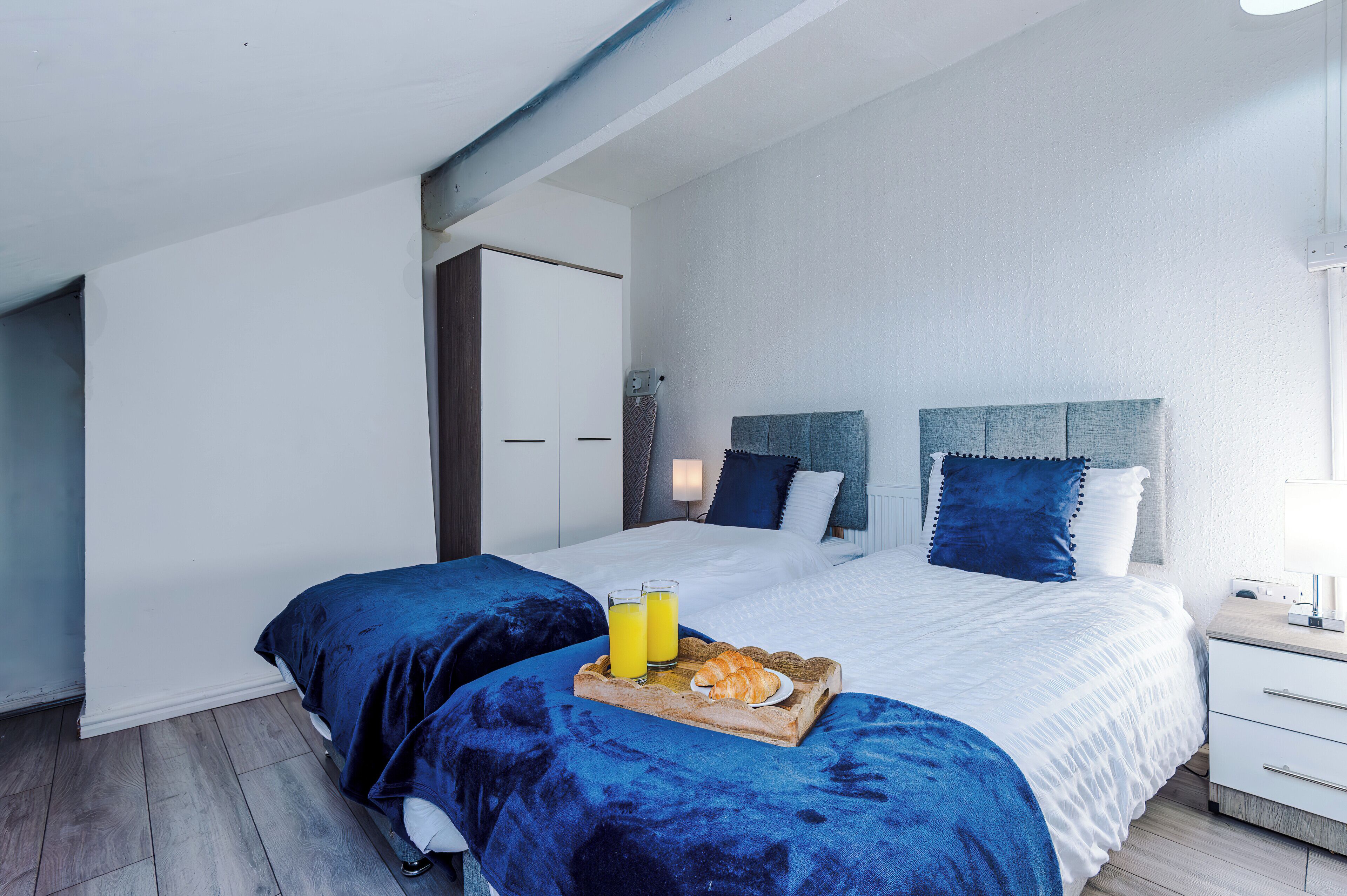 A modern bedroom with a large bed, two bedside tables, and a wardrobe.