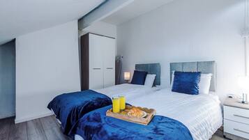 A modern bedroom with a large bed, two bedside tables, and a wardrobe.