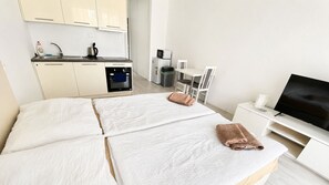 A hotel room with a bed, a TV, a small kitchenette, and a dining area. - 1 room apartment, balcony, Zuzany Chalupovej 18B (Bratislava)