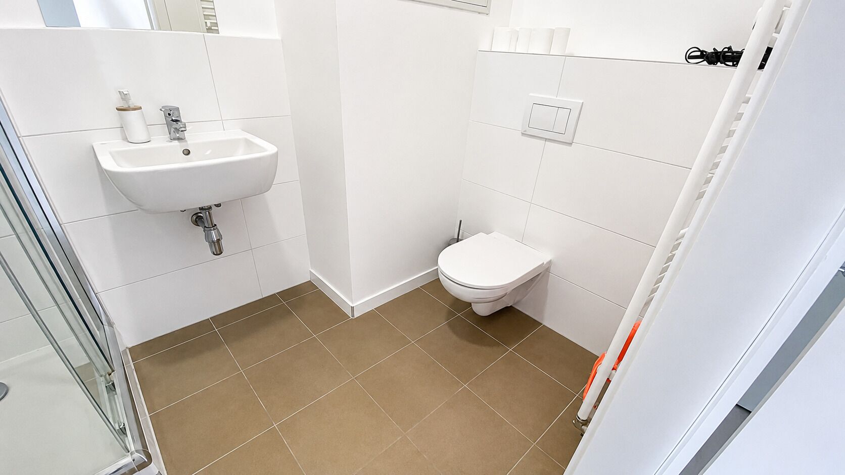 Ein Badezimmer mit einem weißen Waschbecken, einer Toilette und einer Duschkabine.
