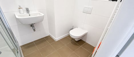 A bathroom with a white sink, a toilet, and a shower area.