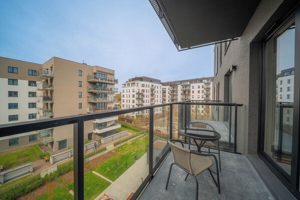 Un balcon avec une table et des chaises, donnant sur un quartier résidentiel avec des immeubles modernes.