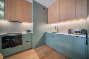 Une cuisine moderne avec des meubles en bois, un lave-vaisselle intégré et un plan de travail sur lequel se trouvent une bouilloire et une machine à café.