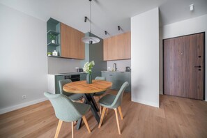 Une cuisine moderne avec des meubles en bois, une table de salle à manger ronde et des chaises recouvertes d’un tissu vert.
