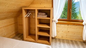 Una habitación de madera con armario empotrado, una cama y una ventana con cortinas.