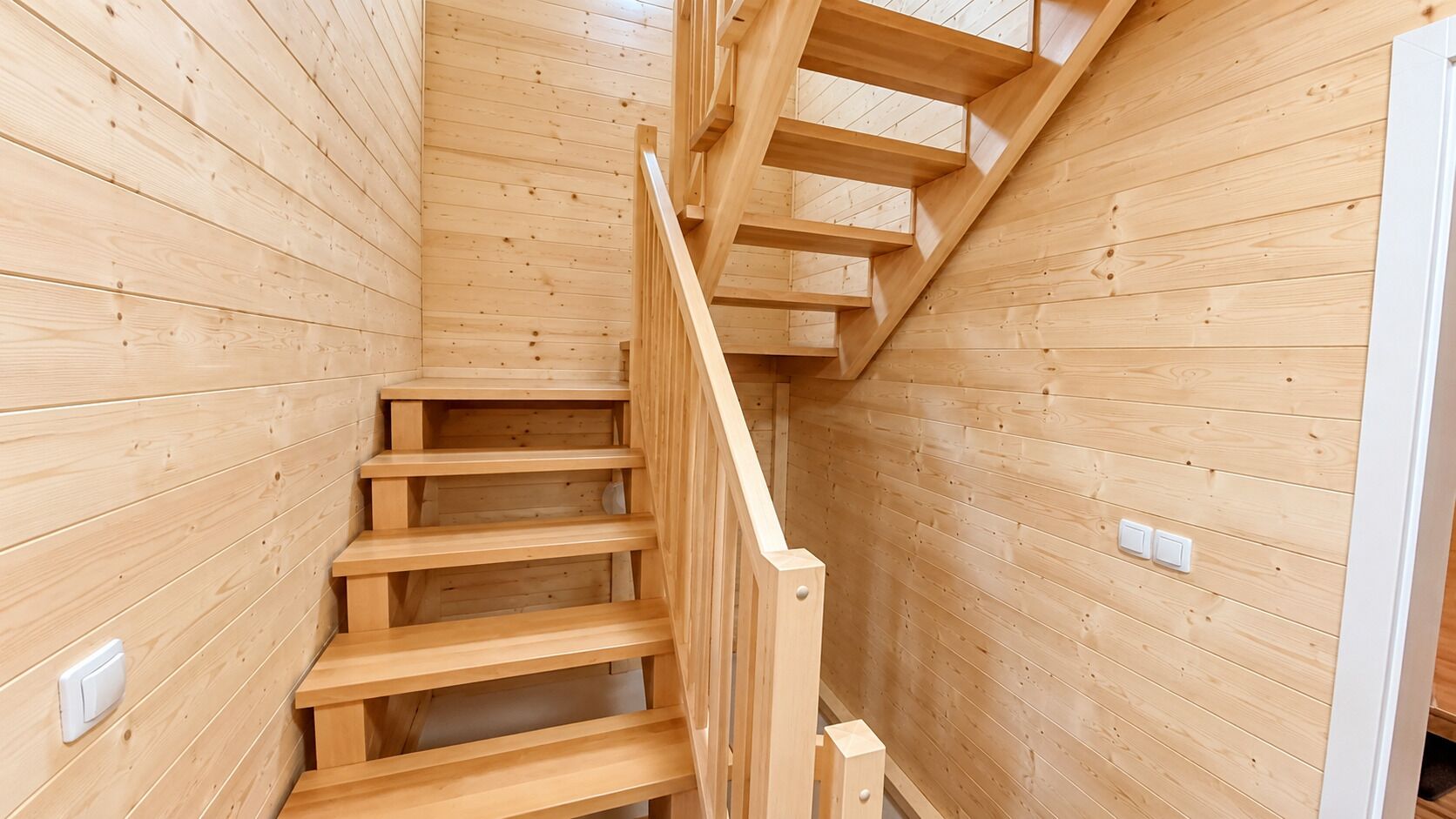 A wooden staircase with a handrail, leading to an upper level.