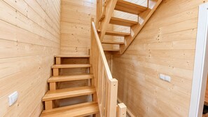 A wooden staircase with a handrail, leading to an upper level.