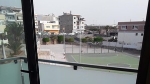 Uma varanda com vista para um campo esportivo e edifícios.