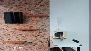 Uma cozinha moderna com parede de tijolos, TV de tela plana, micro-ondas e mesa de jantar com cadeiras.