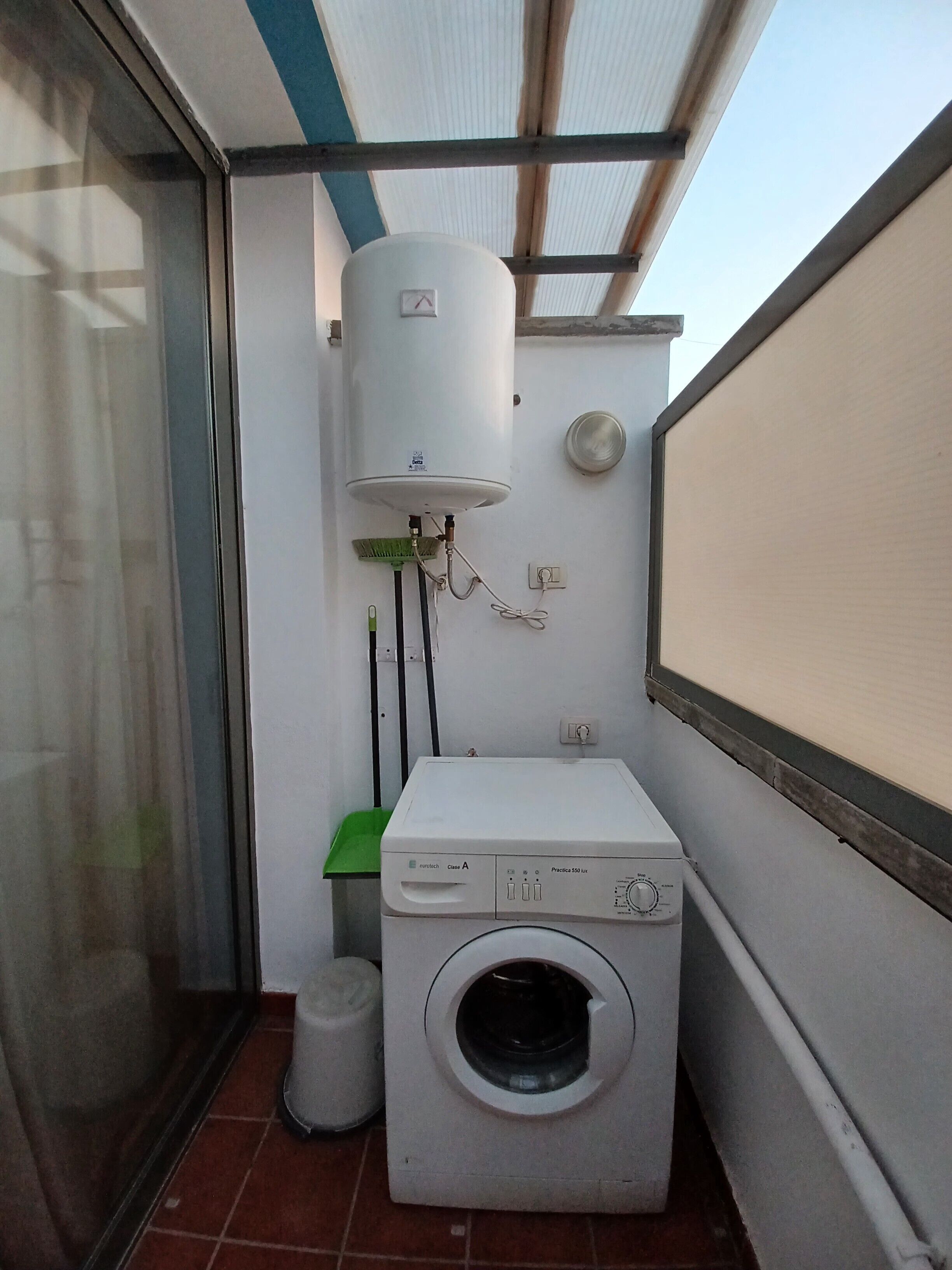 Een kleine wasruimte met een wasmachine en een boiler.