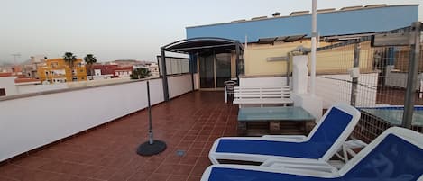 Une terrasse sur le toit dotée d’un espace salon couvert, d’une table et de fauteuils de détente.
