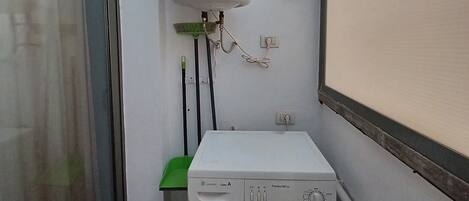 Un petit espace buanderie comprenant un lave-linge et un chauffe-eau.