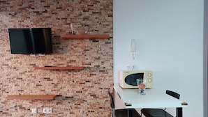 Uma cozinha moderna com parede de tijolos, TV de tela plana, micro-ondas e mesa de jantar com cadeiras.