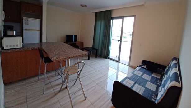 Um espaço compacto com cozinha compacta, área de refeições e cama.