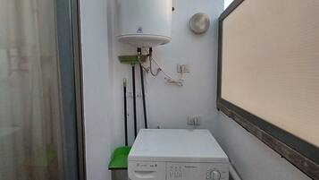 Een kleine wasruimte met een wasmachine en een boiler.
