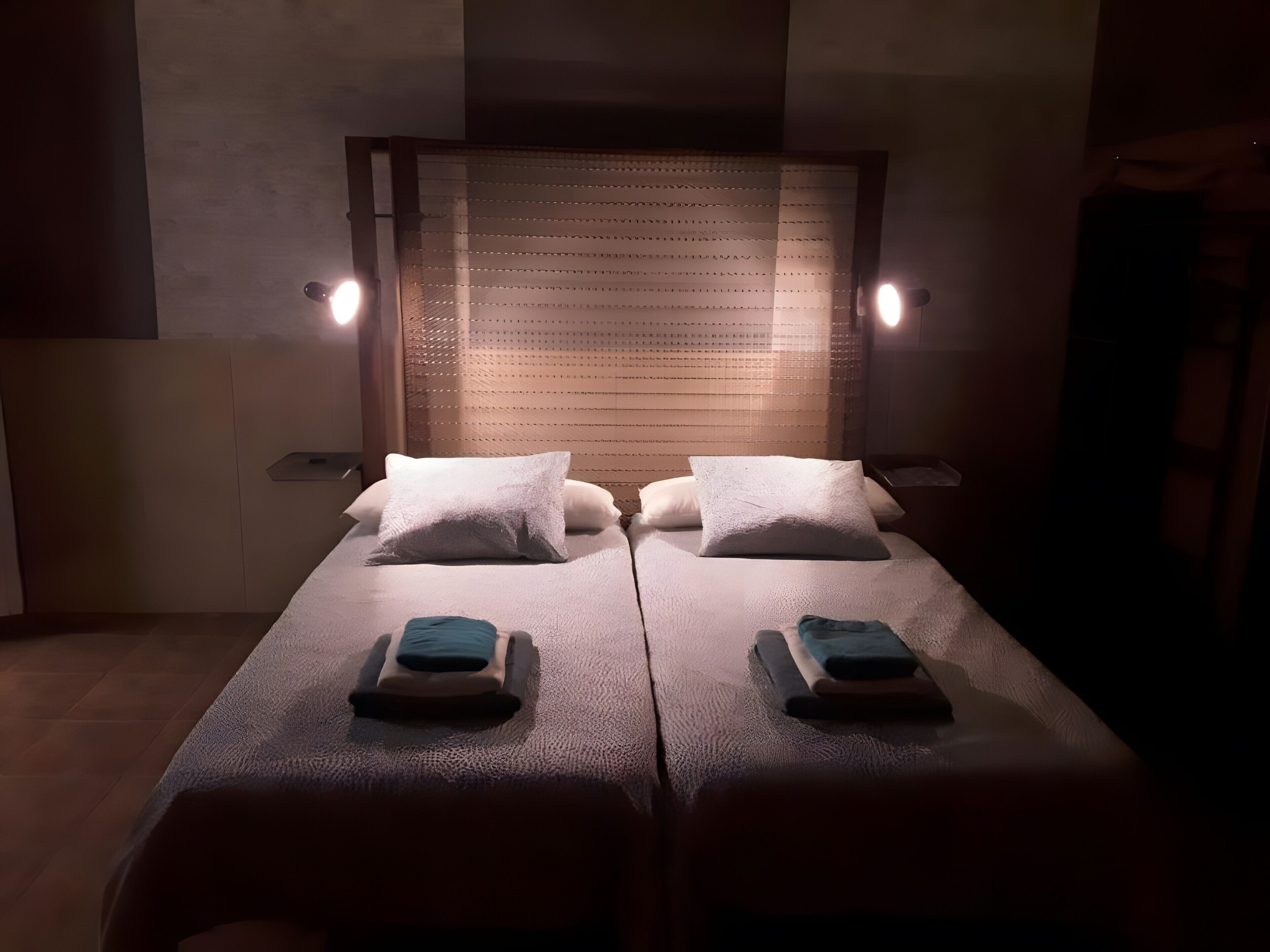 Een kamer met twee bedden, elk voorzien van een kussen en een opgevouwen handdoek.