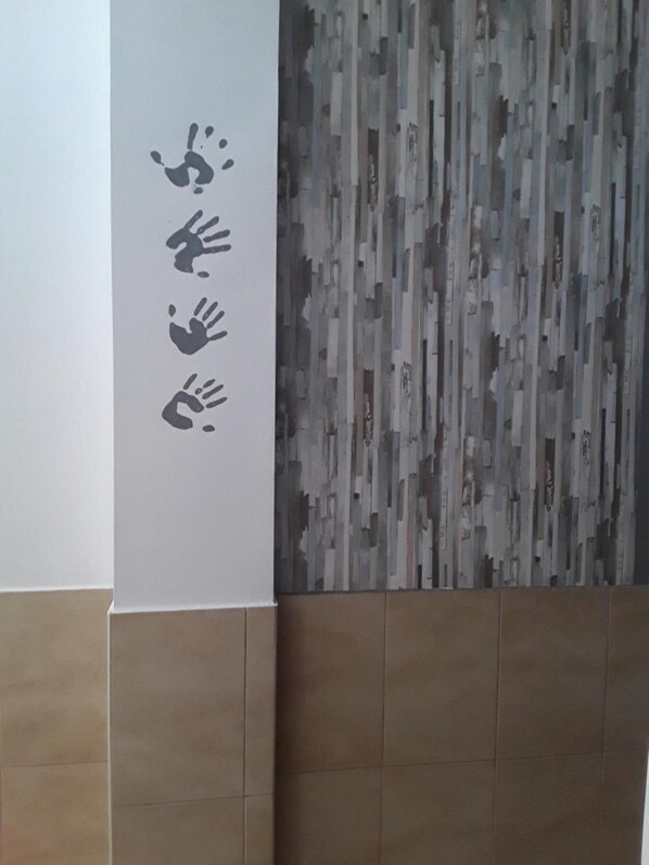 A wall with a vertical strip of handprints and a textured wall panel.