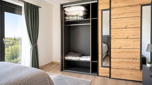 A bedroom with a bed, a wardrobe, a mirror, and a view of the outdoors. - Modern 2 room apartment with terrace, Chrenoviská (Liptovský Mikuláš)