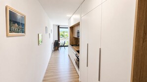 A modern kitchen with white cabinets, a wooden countertop, and a view to the outside. - Modern 2 room apartment with terrace, Chrenoviská (Liptovský Mikuláš)