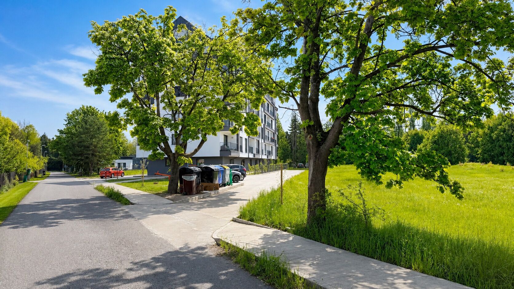 A residential street with a row of houses, a sidewalk, and a grassy area.
