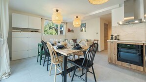 Une cuisine moderne avec une table à manger, des chaises et des luminaires suspendus.