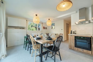 A modern kitchen with a dining table, chairs, and pendant lights. - Cimes - Modern, Sleeps 8 | New | Family-Friendly | Quiet Location (Chamonix)