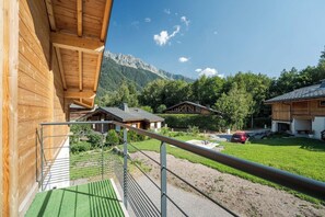 A wooden cabin with a balcony overlooking a mountain landscape.
