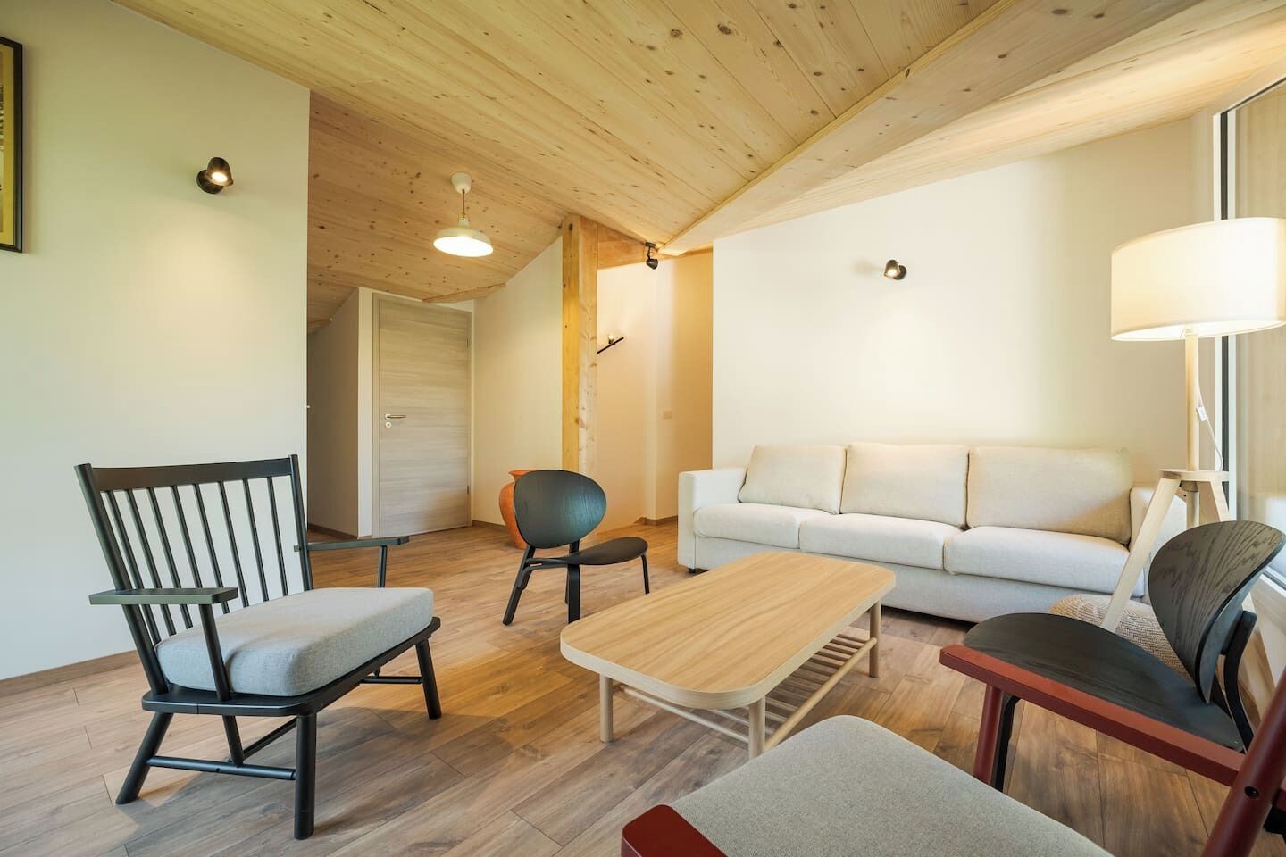 A modern living room with a sofa, chairs, a coffee table, and a lamp.