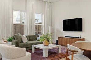 A modern living room with a sofa, coffee table, and a TV mounted on the wall. - Stylish 3-bedroom house in Houston Great Location - Near Med Center, Energy (Houston)