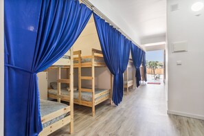 A room with bunk beds, blue curtains, and a wooden floor. - Open-space Hostel for Groups – Near Ericeira and Mafra (Mafra)