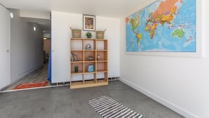 Une pièce avec une bibliothèque en bois, un tableau encadré, une grande carte du monde et un tapis à rayures.