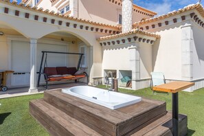 A spa area with a wooden deck, a hot tub, and a swing chair. - Open-space Hostel for Groups – Near Ericeira and Mafra (Mafra)