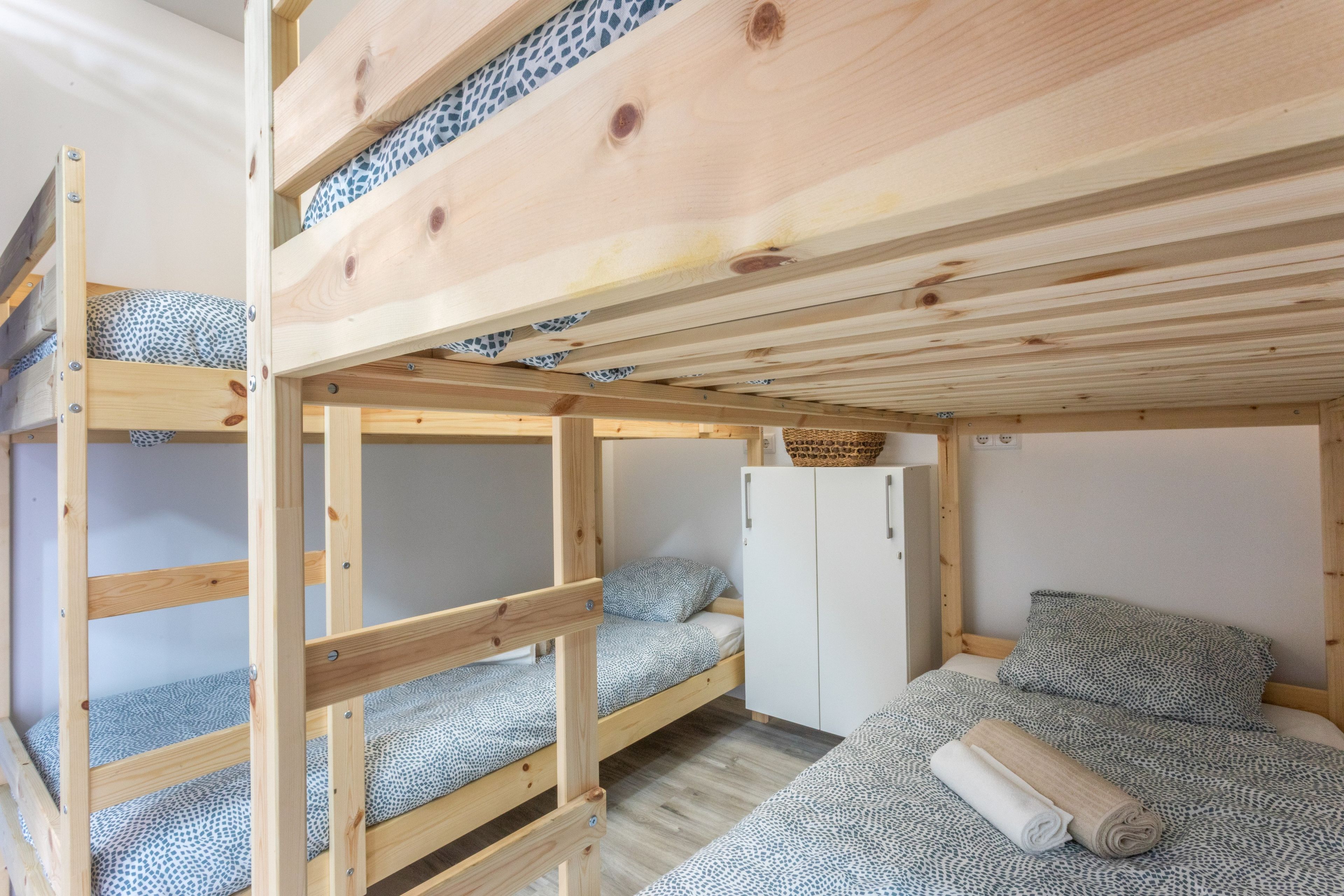 Une chambre avec un lit superposé, une armoire et un petit meuble de rangement.