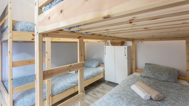 Une chambre avec un lit superposé, une armoire et un petit meuble de rangement.