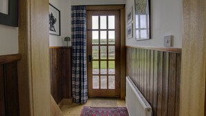 Un corridoio con una porta in legno, vista all'esterno e un termosifone sulla parete.
