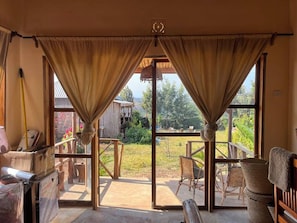 A room with large windows, wooden furniture, and a view of the outdoors. - Oloresho Safari Lodge (Arusha)
