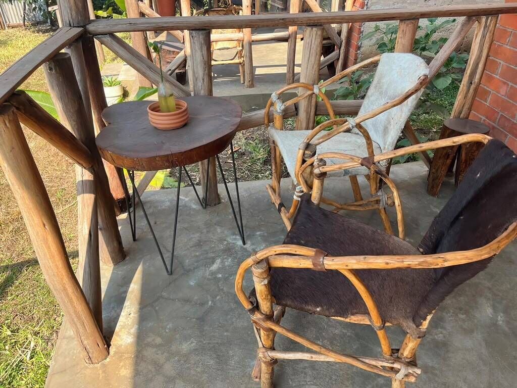 Una terraza de madera con una mesa redonda y dos sillas de mimbre.