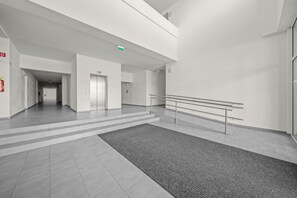 Een ruim, modern interieur met een centrale trap, een brandblusser links en een rookmelder rechts.