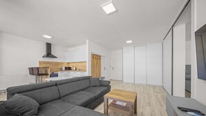 A modern living room with a grey sectional sofa, a wooden coffee table, and a TV stand with a remote control. - 2 room Apartment with balcony-Nálepkova (Liptovský Mikuláš)