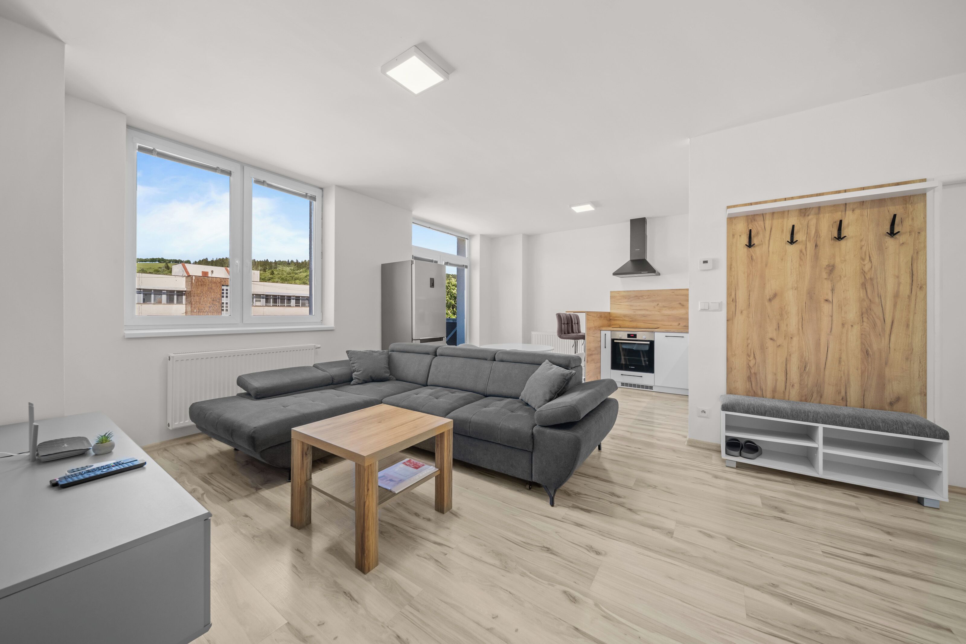 A modern living room with a sectional sofa, a wooden coffee table, and a view of the outdoors.