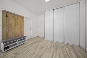 Huone, jossa on puinen seinä, penkki ja liukuovilla varustettu vaatekaappi.