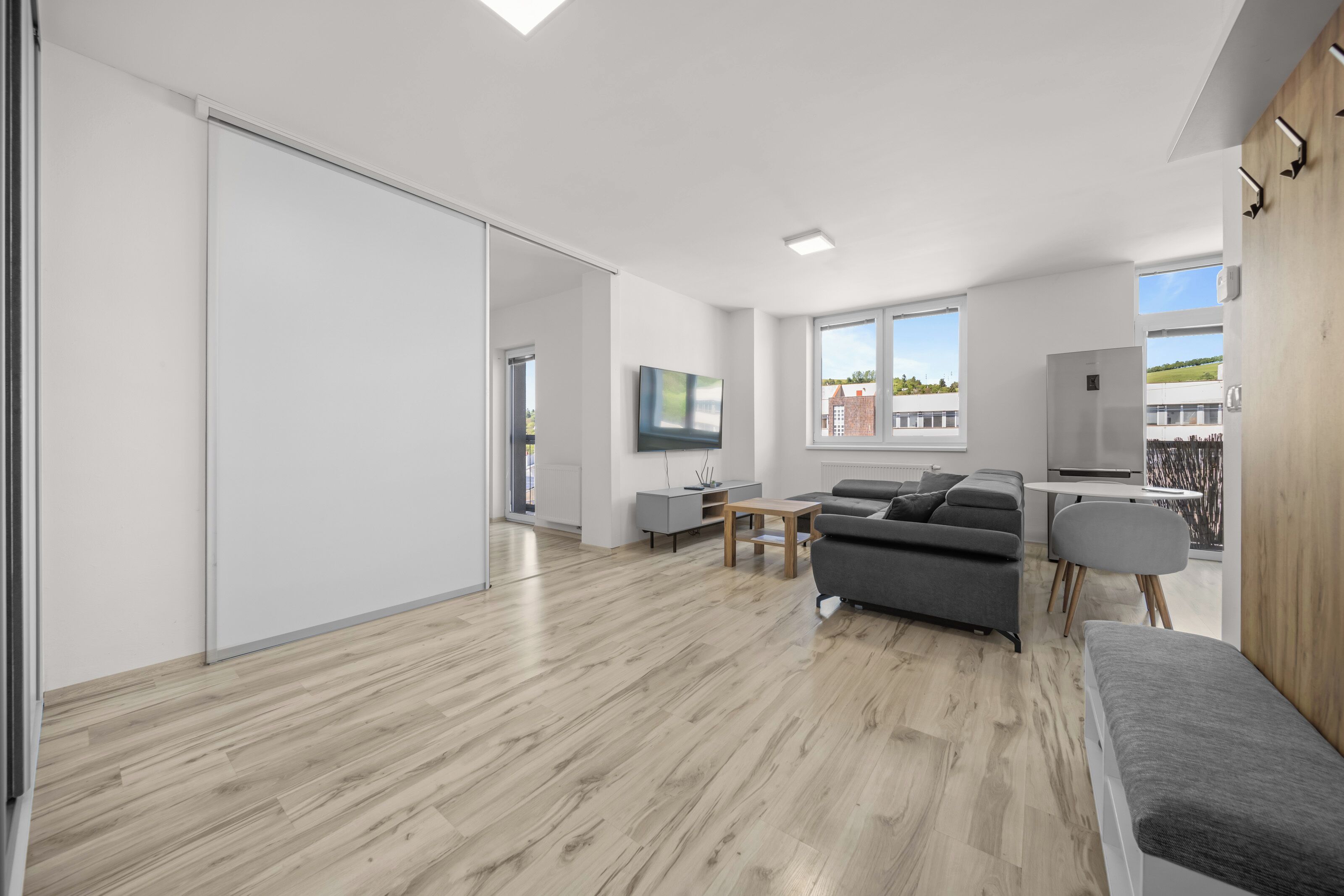 Un espacio habitable moderno con una puerta corredera, un sofá gris, una mesita y vistas al exterior.